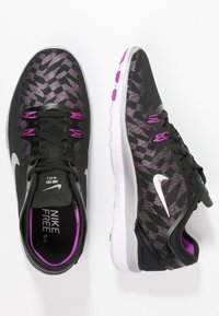 Schwarze Nike Free 5.0 Sneaker mit einem strukturierten Design, lila Akzenten, einem leichten Mesh-Obermaterial und einem weißen Swoosh-Logo.