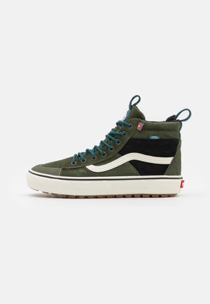 High-top Vans sneaker in olijfgroen en zwart met een witte zijstreep, groenblauwe veters en een witte rubberen zool met een getextureerde bruine buitenzool.
