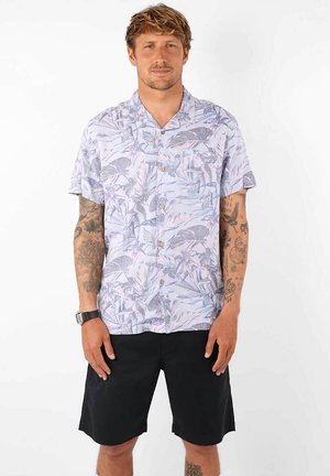 Chemise à manches courtes avec boutons de couleur violet clair, à motif de feuilles tropicales, associée à un short noir. Le tissu semble léger et respirant.