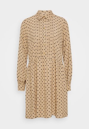 Vestido beige de manga larga con lunares negros, cuello puntiagudo, tapeta de botones frontal y cintura fruncida.