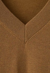 Pull en V d'une couleur marron chaud, fabriqué en tissu tricoté texturé avec des détails de couture visibles autour de l'encolure.