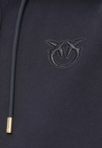 Μπλε ναυτικό φούτερ με υφή υφάσματος που διαθέτει ανάγλυφο λογότυπο στο κέντρο. Περιλαμβάνει χρυσό φερμουάρ και κορδόνι.