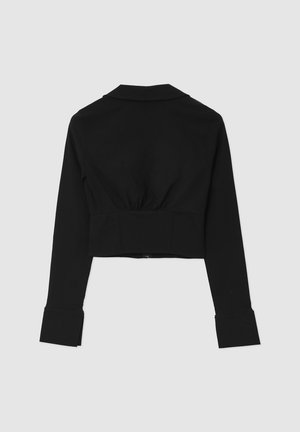 Schwarze, kurze Jacke mit langen Ärmeln, einem Kragen und elastischen Raffungen an der Taille. Verfügt über breite Bündchen und eine glatte Textur.