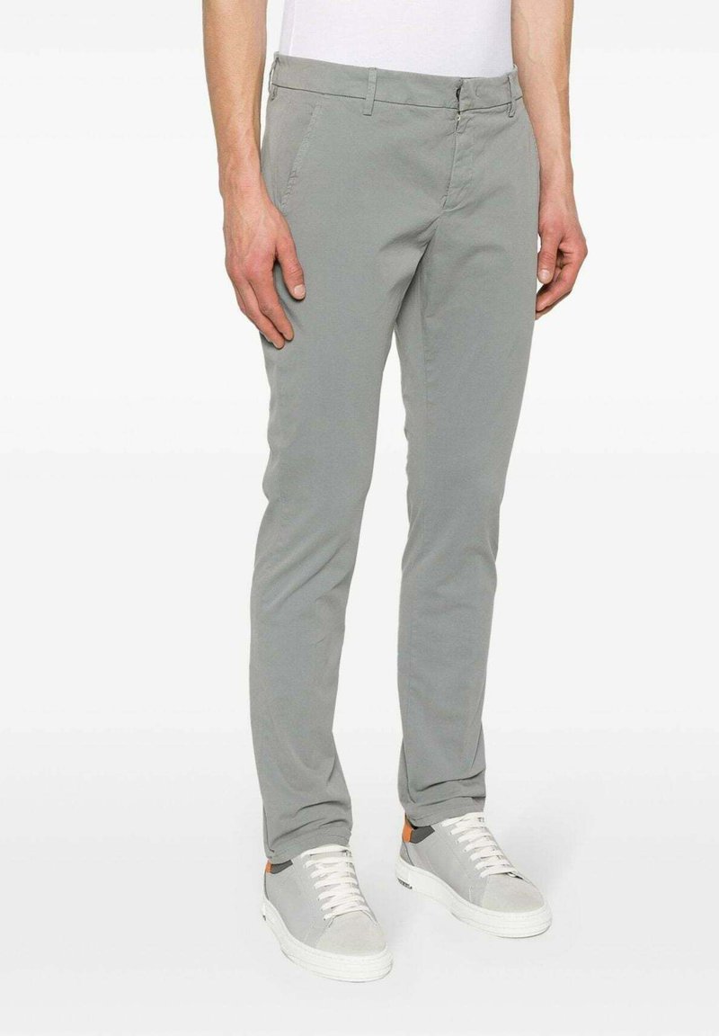 Chino slim-fit grigio chiaro, con una texture liscia, gambe leggermente affusolate, tasche anteriori e una chiusura discreta con bottone e zip.