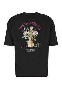 Μαύρο T-shirt με ανθοδέσμη σε βάζο, ροζ κείμενο "PAS DE MONACO" πάνω και λευκό κείμενο "FLORALE À FLEUR DE PEAU" κάτω.