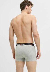 Pilki medvilniniai bokseriai su juodu juosmeniu, ant kurio raudonomis raidėmis išsiuvinėtas prekės ženklas "JACK & JONES", matomi iš nugaros.