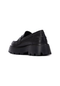 Zapatos negros de cuero sin cordones con una suela de goma gruesa que presenta surcos texturizados y un detalle cosido en el lateral.