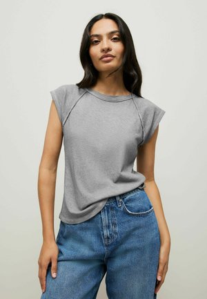 Gray, short-sleeve top made of soft fabric with a round neckline and raglan sleeve design, paired with high-waisted blue jeans.