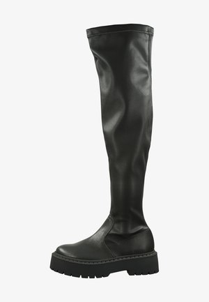 Knöchelhohe schwarze Stiefel aus Kunstleder mit einer flachen, stabilen Sohle und seitlichem Nahtdesign. Glatte Textur mit einem eleganten, körperbetonten Schnitt.