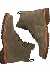 Bruna mockaskinnankelboots med snörning, gummiflätad sula, tan-färgad trä-mellansula och dragöppning på hälen. Texturerad yta och förstärkta ögla.