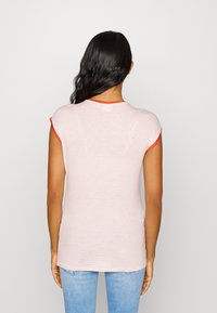 Camiseta a rayas en rosa claro y rojo con mangas cortas y cuello rojo. Tejido suave, diseño ajustado y dobladillo recto.