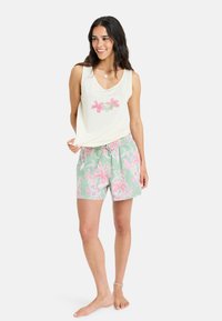 Helles gelbes ärmelloses Oberteil mit rosa Blumenstickerei, kombiniert mit mintgrünen Shorts, die rosa Blumenmuster und einen elastischen Bund haben.