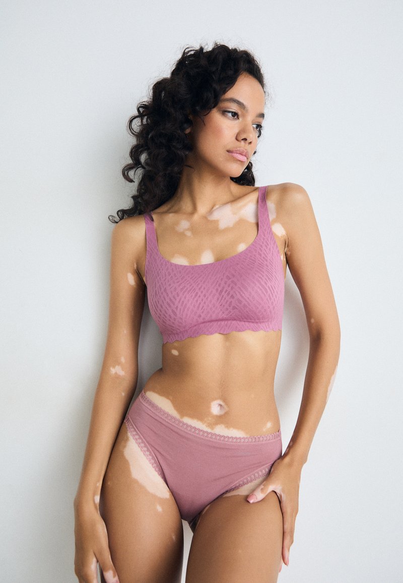 Light pink bralette with a textured pattern and scalloped edges, paired with matching panties featuring delicate lace trim.