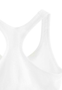 White sports bra featuring a racerback design. Made of ribbed fabric with smooth texture and minimal seams for comfort.