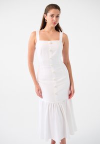 Robe midi blanche ajustée avec décolleté carré, bretelles ajustables, détail de boutons sur le devant et ourlet à volants, confectionnée en tissu léger.