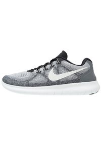 Scarpa da running Nike grigia e nera con logo swoosh bianco, lacci neri e suola bianca spessa, mostrata in profilo laterale su sfondo bianco.
