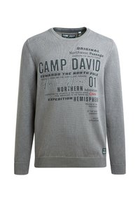 Grau gestrickter Pullover mit Rundhalsausschnitt, gerippten Bündchen und Saum. Aufdruck mit Text in verschiedenen Schriftarten und Größen auf der Vorderseite. Etikett an der Seite.