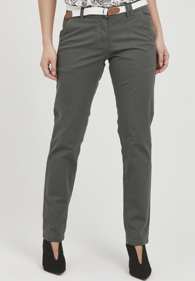 Pantalons gris en mélange de coton avec une coupe slim, dotés de poches avant et d'une ceinture marron. Portés avec des chaussures à talons noires. Texture unie.