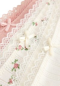 Blødt strikstof i lyserøde og cremefarvede toner med blonderkanter, små blomsterprint og små satinbuer langs kanten.