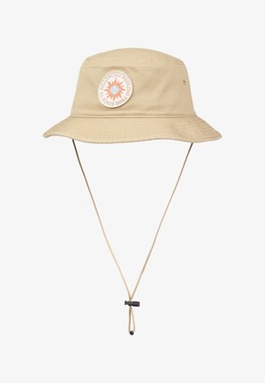 Beżowy kapelusz typu bucket z szerokim rondem, regulowanym paskiem pod brodą oraz okrągłą naszywką z motywem słońca i tekstem z przodu.