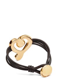 Pulsera de cordón de cuero negro con un centro en forma de corazón de metal en tono dorado, que presenta una textura suave y un acento de nudo para el cierre.