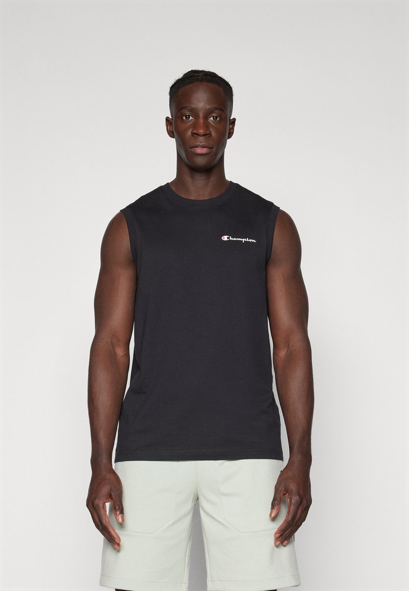 Camiseta de algodón negra sin mangas con cuello redondo y pequeño logotipo bordado en blanco en el pecho, combinada con pantalones cortos verde claro.