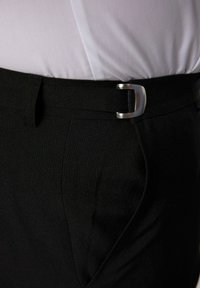 Pantalones de tela negra con una hebilla plateada en la cintura, con una textura suave y un diseño ajustado, que enfatiza líneas elegantes y funcionales.