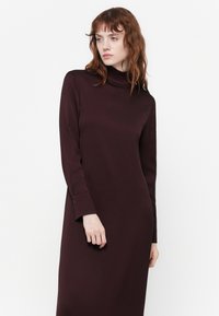 Robe à manches longues en bordeaux profond, dotée d'un col montant et d'un buste ajusté, avec une silhouette droite et des poignets boutonnés.