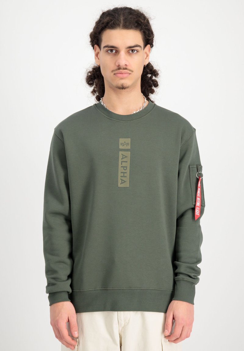 Grøn sweatshirt lavet af en bomuldsblanding, med et frontlogo i dæmpet grøn, ribbede manchetter og en sidelomme med et rødt mærke.