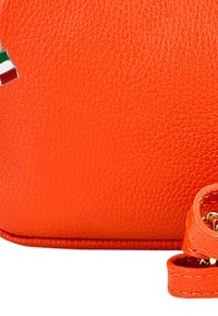 Helle orange Lederhandtasche mit strukturierter Oberfläche, runder Form und einem geschwungenen Riemen mit goldenen Beschlägen und einem Logoakzent.