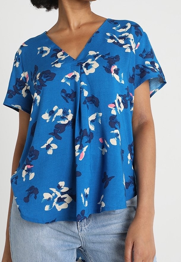 Blue floral blouse made of lightweight fabric. Features a v-neck, short sleeves, and abstract white and dark blue patterns. Casual fit.