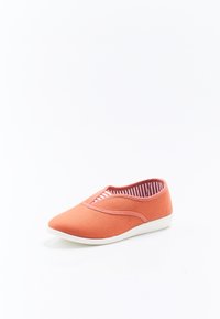 Zapatilla de lona naranja tipo slip-on con punta redonda, que presenta un forro interior a rayas y detalles elásticos en la parte superior para mayor flexibilidad.