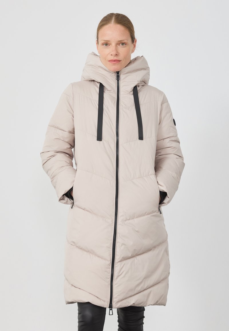 Lys beige pufferjakke med hette, frontglidelås og sorte snorer. Har skrå quilting og sidelommer; glatt tekstur.