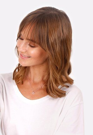Roségoldene Halskette mit einem runden Anhänger, getragen über einem weißen Hemd. Der Anhänger hat ein einfaches Design und eine zarte Kette.