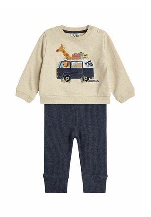 Beige sweatshirt with animal-embroidery detail on a van, paired with dark blue ribbed pants. Includes button closure on the shoulder.