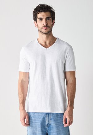 T-shirt blanc à manches courtes avec un col en V, fabriqué en tissu léger, présentant une texture lisse et une coupe décontractée.
