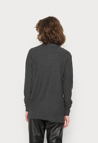 Mörkgrå kofta med långa ärmar, tillverkad av strukturerad tyg; har en ribbad nederkant och muddar, visad bakifrån.