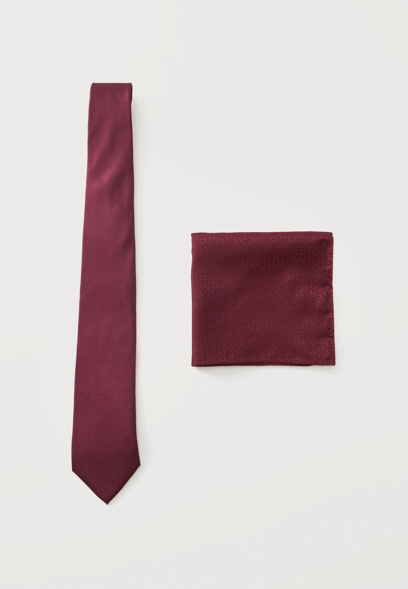 Cravate en soie bordeaux et pochette assortie, posées à plat sur un fond blanc.