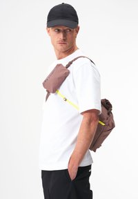 Brauner, wetterfester Rucksack mit verstellbaren Trägern und gelbem Reißverschlussakzent. Leichtes Design, geeignet für Outdoor-Aktivitäten.