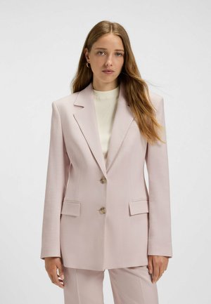 Helle rosa Blazer mit spitzen Revers, zwei Knöpfen, Fronttaschen und taillierter Form, aus glattem Stoff gefertigt. Kombiniert mit einem leichten Pullover.