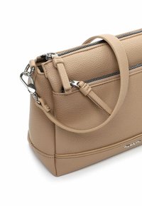 Bēša ādas rokassomiņa ar reljefu virsmu, tai ir augšējā rāvējslēdzējs, plecu siksna un maza priekšējā kabata ar sudraba metāla detaļām.