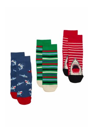 Trzy pary kolorowych skarpetek: niebieskie z wzorem rekinów i ryb, zielone w wielokolorowe paski, czerwone z białymi paskami i wzorem paszczy rekina.