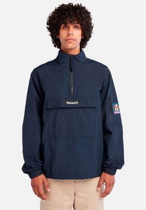 Mørkeblå, lett genserjakke med halv-zip foran, elastiske mansjetter og en brystlomme med Timberland-logo og -lapp.