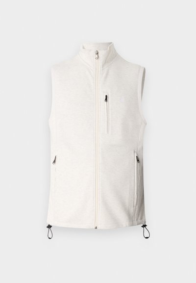 Ανοιχτό μπεζ χωρίς μανίκια γιλέκο με ψηλό γιακά, μπροστινό φερμουάρ και τσέπες με φερμουάρ. Διαθέτει ρυθμιζόμενα κορδόνια στο τελείωμα. Μαλακή υφή.