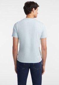 Tricou de culoare albastru deschis, cu mânecă scurtă și guler rotund, realizat din bumbac moale, având o textură fină și detalii de design minime.