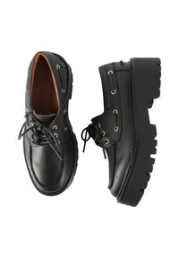 Scarpe di pelle nera con punta arrotondata, suola spessa in gomma nera e occhielli metallici per i lacci. L'interno è in pelle marrone.