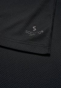 Schwarzes Sportshirt mit strukturiertem Mesh-Muster. Verfügt über ein Logo in Hellgrau und eine Nahtverzierung entlang der Kanten.