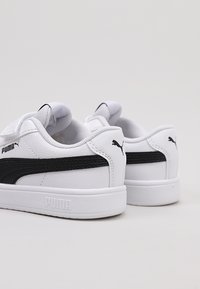Sneaker bianche con accenti neri, materiale in pelle liscia, punta rotonda, suola piatta e marchio Puma ben visibile sul tallone e sul lato.