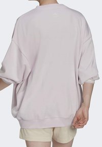 Rosa oversize sweatshirt med ribbad fåll och muddar. Har en liten, ton-i-ton logga baktill. Mjuk textur, avslappnad passform.