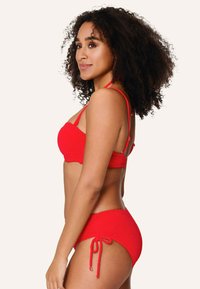 Červený bikinový set s texturovanou látkou, s řaseným topem, nastavitelnými ramínky a vysokými kalhotkami se šňůrkovými detaily.